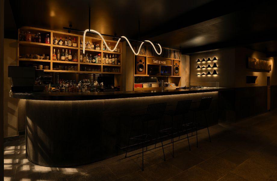 The bar at Cafe de Nadie in Roma Norte, with a neon sign above the back bar