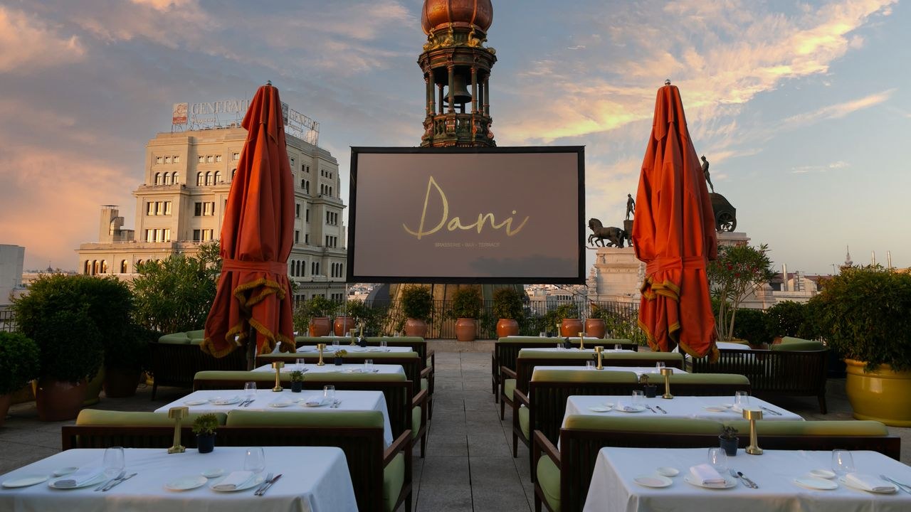 The terrace at Dani Brasserie on the roof of the Four Seasons Madrid at dusk, with a cupola and quadriga behind