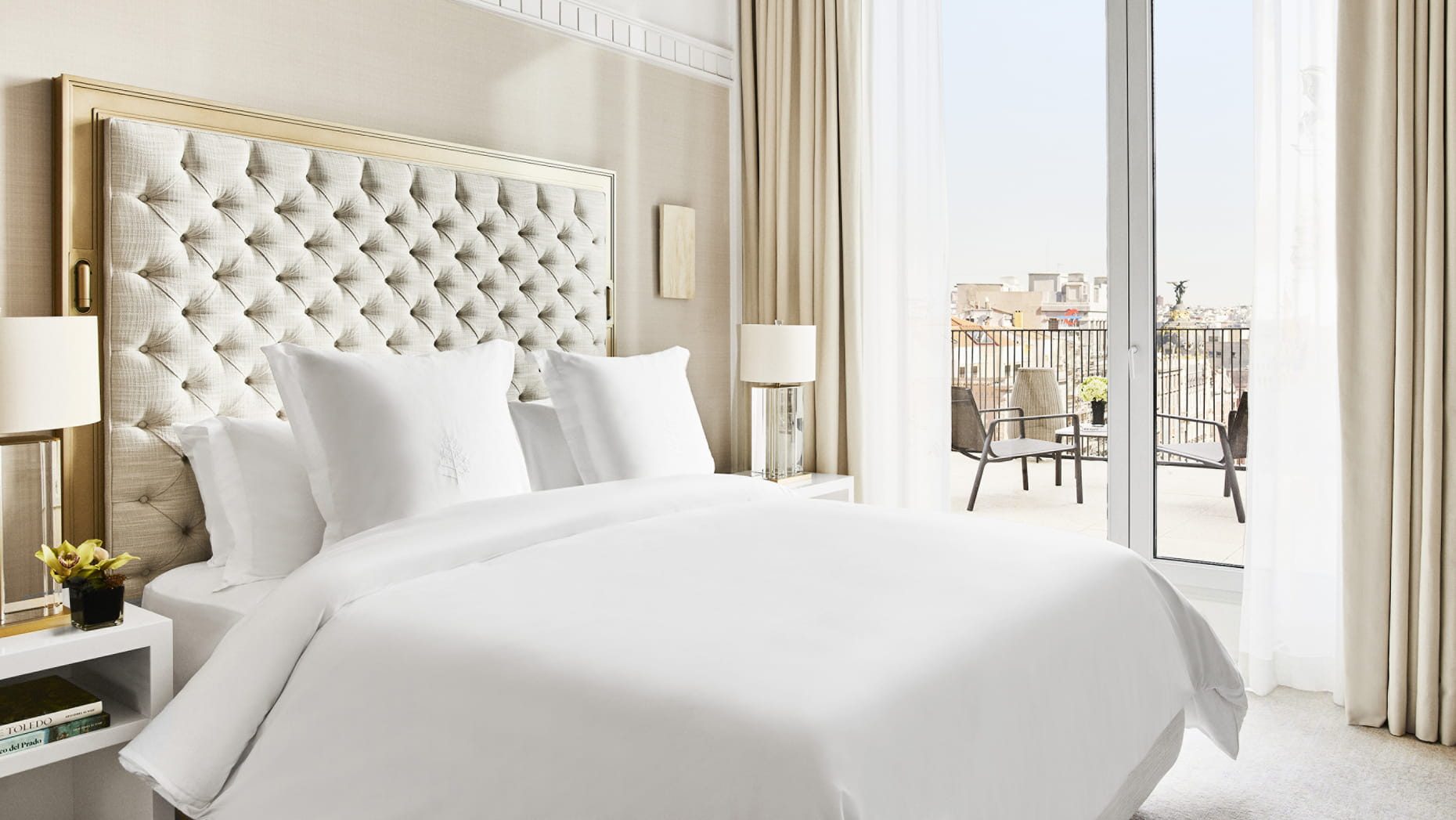 A Four Seasons Madrid bedroom with a tufted headboard and a terrace overlooking the rooftops
