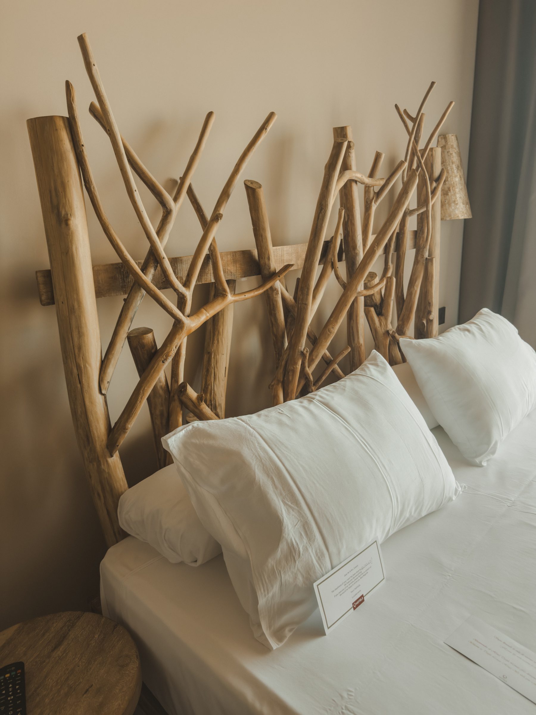 A hotel bed with a headboard made from driftwood branches
