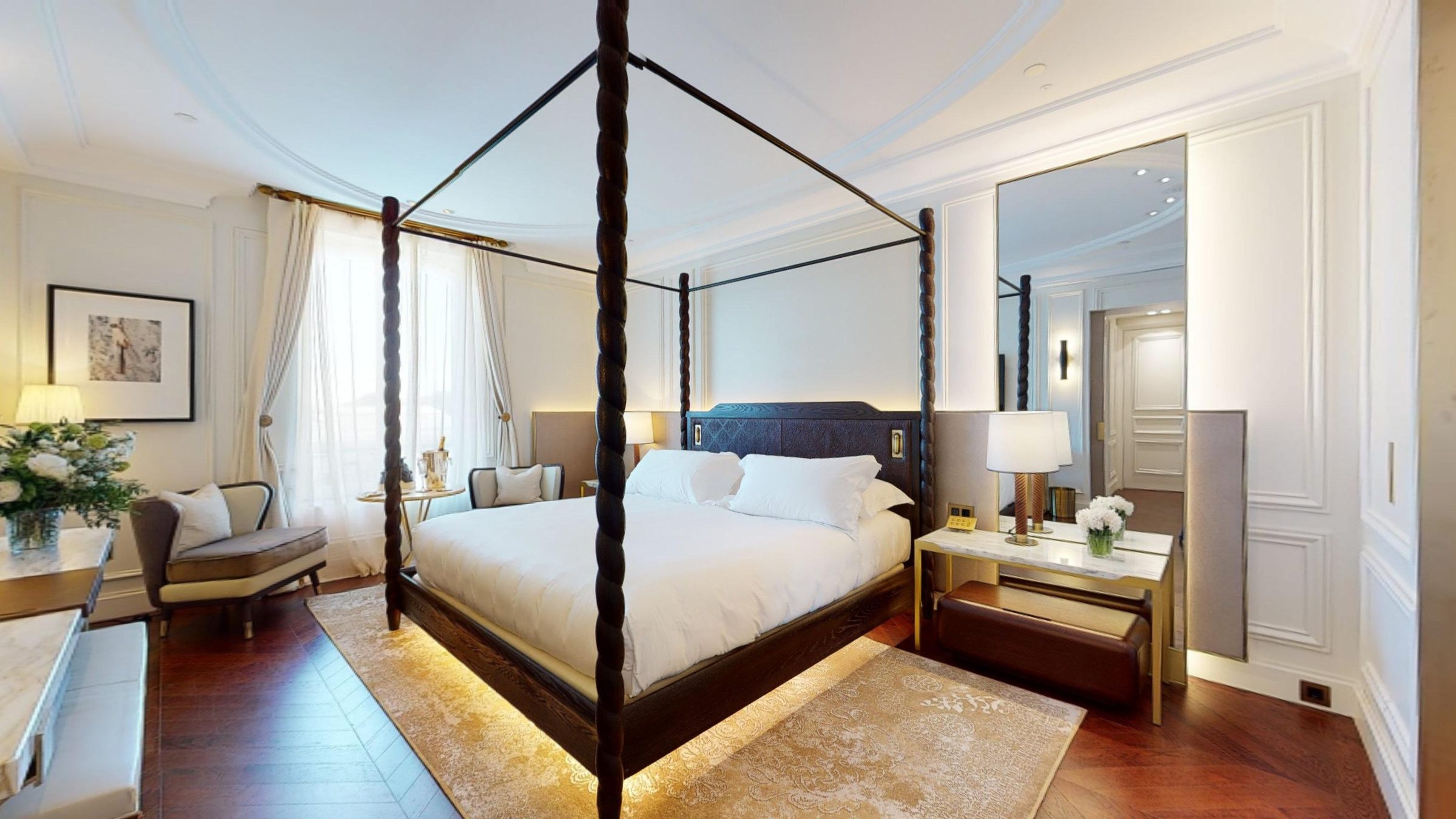 A room at the Mandarin Oriental Ritz Madrid with a carved four poster bed and tall windows