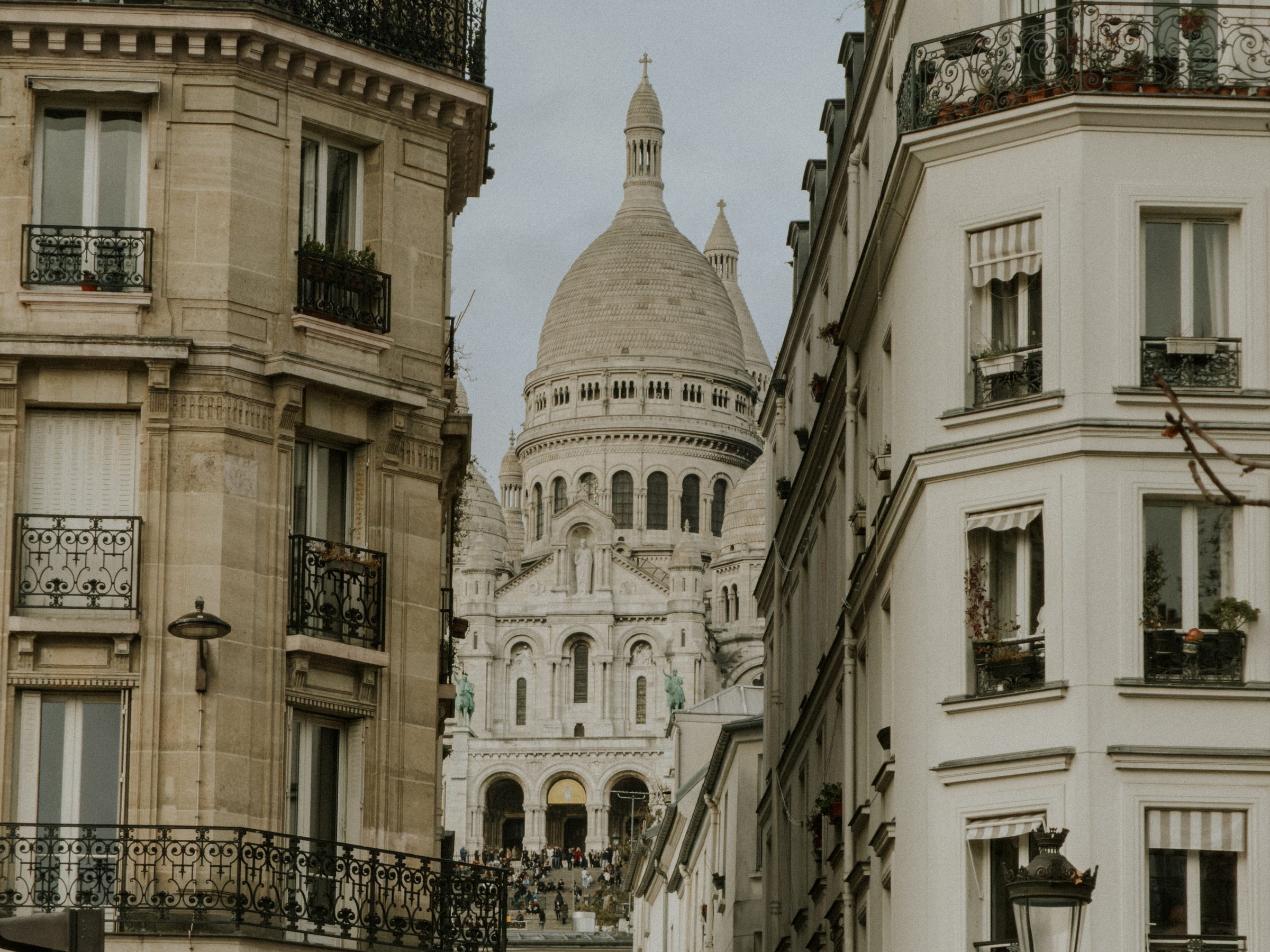 Sacre-Coeur seen at the end of a Paris street framed by Haussmann buildings
