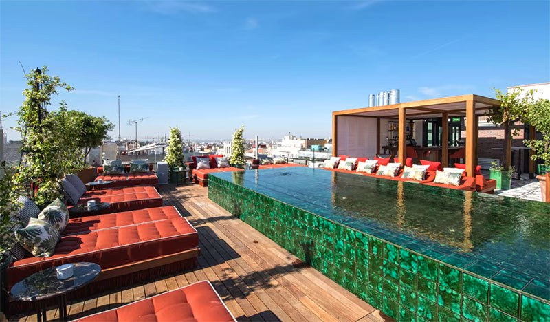The green tiled infinity pool and orange daybeds on the rooftop at Picos Pardos, BLESS Hotel Madrid