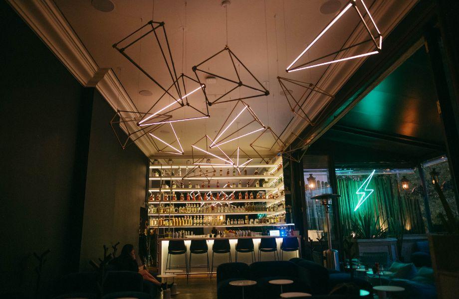 The interior of Rayo in Mexico City, with geometric neon light sculptures above the bar